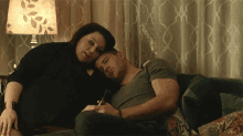 a man and a woman are laying on a couch with the woman hugging the man