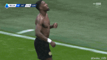 a shirtless man stands in front of a microphone on a field during a soccer match