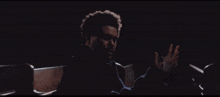 a man sitting in a dark room with his hand outstretched