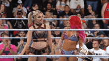 two women are standing in a wrestling ring and one has a championship belt