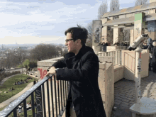 a man stands on a balcony with graffiti on the railing including the letters y and z