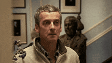 a man stands in front of a statue of a man in a suit