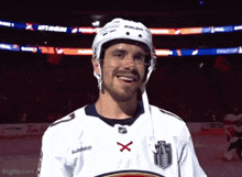 a hockey player wearing a bauer helmet and a white jersey