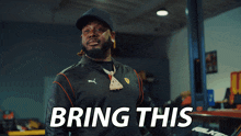 a man in a black puma jacket says bring this in white letters