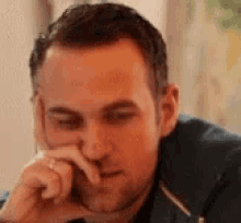 a close up of a man 's face with his hand on his face .