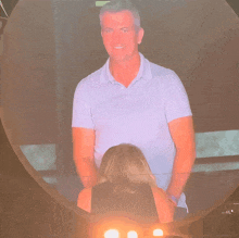 a man in a blue shirt stands in front of a woman