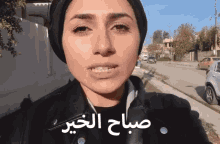 a woman wearing a black head scarf and a black jacket with arabic writing