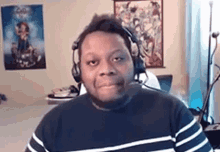 a man wearing headphones and a striped shirt is sitting in front of a computer in a room .
