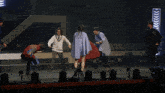 a group of people are dancing on a stage with arrows in the back