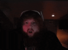 a man with a beard is wearing a hoodie and sunglasses in the dark