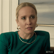 a woman wearing hoop earrings and a necklace is sitting on a couch with netflix written on the bottom