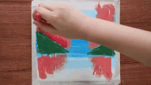 a person is painting a picture of christmas trees on a piece of paper
