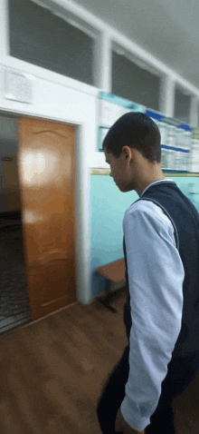 a young man standing in a hallway with a poster on the wall behind him