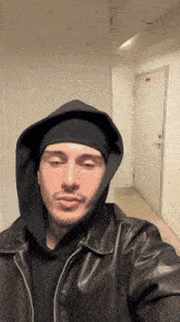 a man wearing a leather jacket and a black beanie