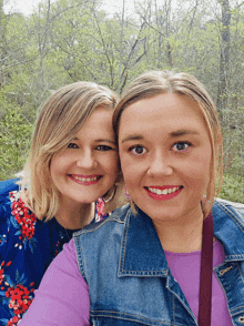 two women are posing for a picture and one is wearing a denim vest
