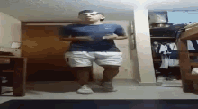 a man in a blue shirt and white shorts is standing in a room with a closet in the background .