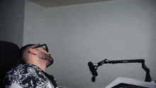 a man wearing sunglasses sits in front of a microphone
