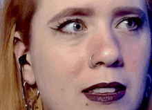a close up of a woman 's face with a piercing in her nose