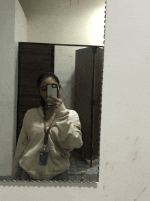 a woman taking a picture of herself in a mirror with her phone