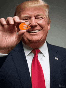 a man in a suit and tie is smiling and holding an orange 2df logo in his hand