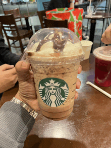 a person is holding a starbucks drink with a crown on it