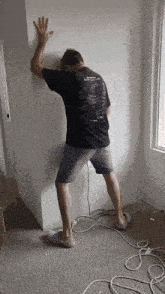 a man is leaning against a wall with his hand up