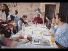 a group of people are sitting at a long table eating food