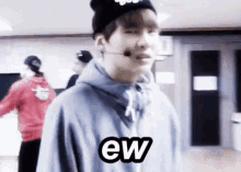 a young man wearing a beanie and a hoodie is making a funny face and says ew .