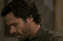 a man with a beard wearing a green shirt looks down