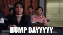 a woman is sitting in a classroom with a group of people and the words hump day .