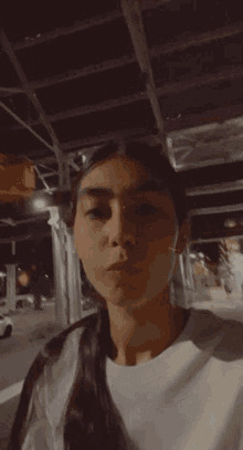 a woman is making a funny face with her mouth open while standing in front of a building at night .