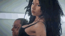 a woman in a black bra is standing in front of a man .