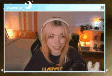 a woman wearing headphones is smiling while sitting in a room .