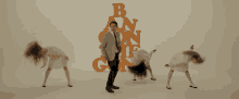 a man in a suit and tie is dancing in front of a stack of letters including b and n