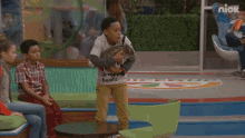 a boy wearing a shirt that says dropping beats holds a turtle