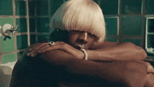 a woman with blonde hair is laying on a man 's back in a bathtub .