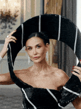 a woman with red nails is wearing a black and white striped dress and earrings