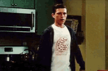 a man wearing a pizza shirt stands in a kitchen