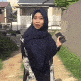 a woman wearing a hijab is walking down a dirt path