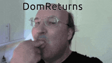 a man wearing glasses and a black shirt with the word dom returns on the bottom