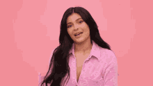 kylie jenner is wearing a pink shirt and sitting in a chair .
