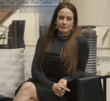 a woman in a black dress sits on a couch