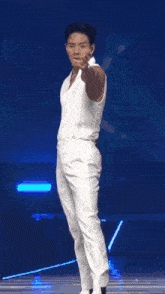 a man in a white tank top and white pants is dancing on stage .