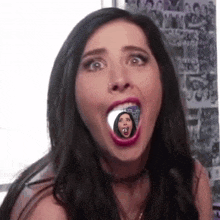 a woman is making a funny face with her mouth open and a picture of herself in it .