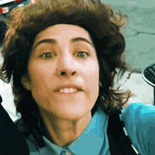 a close up of a woman 's face with a blue shirt on