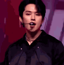 a close up of a man wearing a microphone and a necklace on a stage .