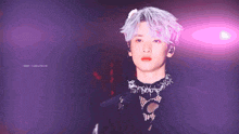 a young man with purple hair is wearing a black top and a necklace