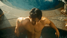 a man without a shirt is standing in a pool