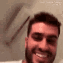 a man with a beard is smiling and looking at the camera in a bathroom .