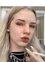 a woman smoking a cigarette wearing a cross necklace